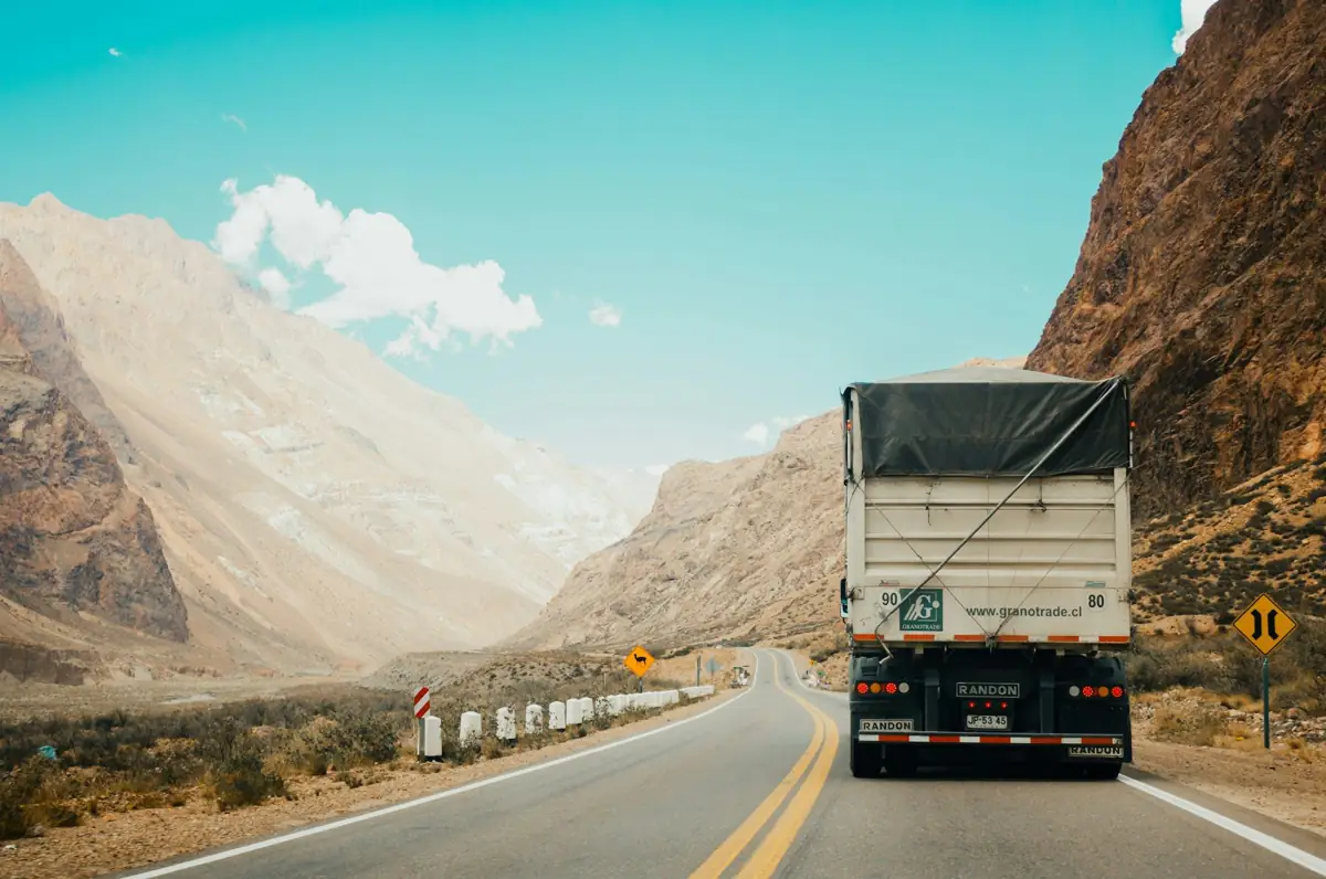 Semi truck climbing a two-lane highway through desert mountains